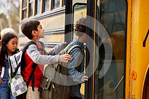 Elementary school kids climbing on to a school bus photo