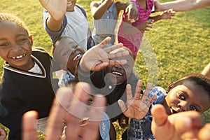 Elementary school kids in a field look up at camera waving