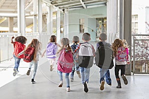 Elementary school kids run from camera in corridor, close up