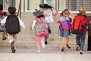 Elementary school kids running into school, back view