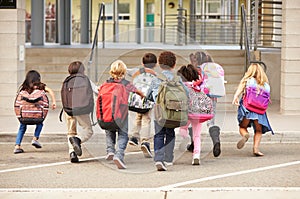 Elementary school kids running into school, back view