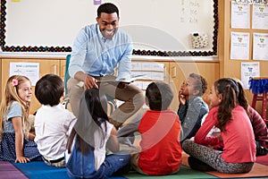 Elementary school kids sitting around teacher in a classroom photo