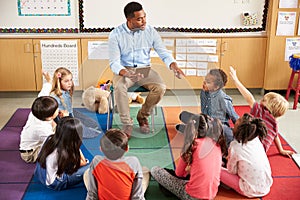 Elementary school kids sitting around teacher in a lesson