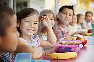 Elementary school kids sitting a table with packed lunches