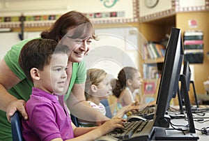 Elementary School Pupil With Teacher In Computer Class