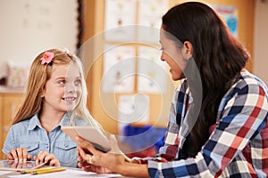 Elementary school pupil and teacher using tablet computer