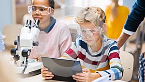 Elementary School Science Classroom: Boy Uses Digital Tablet Computer to Check Information on the