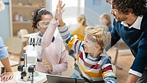 Elementary School Science Classroom: Cute Little Girl Looks Uses Microscope, Boy Uses Digital Tablet