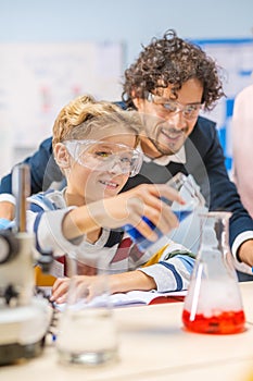 Elementary School Science Classroom: Little Boy Mixes Chemicals in Beakers, Enthusiastic Teacher