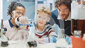 Elementary School Science Classroom: Little Boy Mixes Chemicals in Beakers. Enthusiastic Teacher