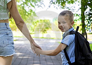 An elementary school student going to study. A first grader holds his mother& x27;s hand and smiles at the camera. The