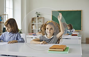 Elementary school student raises her hand, ready to answer the teacher's questions in class.