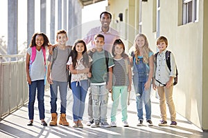 Elementary school teacher and his pupils in school corridor