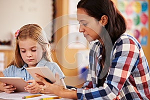 Elementary school teacher and pupil using tablet computers