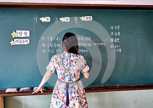 Elementary school teacher at South Korea writing the objectives of the day on a blackboard
