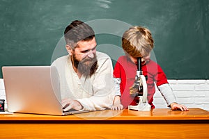 Elementary school teacher and student in classroom. Daddy play with schoolboy. Teacher and schoolboy using laptop in