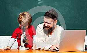 Elementary school teacher and student in classroom. Daddy play with schoolboy. Teacher and schoolboy using laptop in