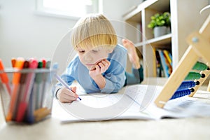 Elementary student boy doing homework at home. Child learning to count, solves arithmetic examples, using abacus. Math tutorial.