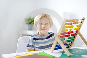 Elementary student boy doing homework at home. Child learning to count, solves arithmetic examples, using abacus. Math tutorial.