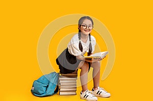 Elementary Student Girl Reading Sitting On Books Stack, Yellow Background
