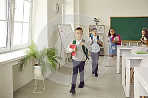 Group of happy elementary school children leaving the classroom at the end of the lesson