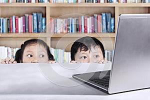 Elementary students peeping laptop in library