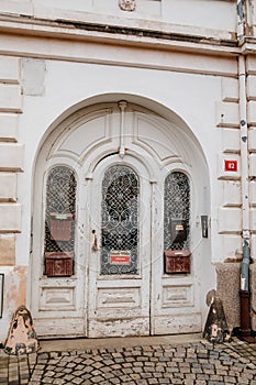Elements of architectural decoration of buildings, old ancient wooden white door on around arch with stone wall, graceful forged