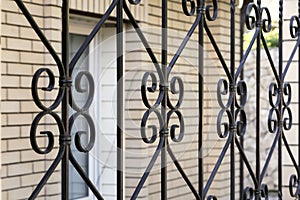 Elements are fragments of a detail of a forged black painted decorative fence made of metal. House fencing, grille, protection,