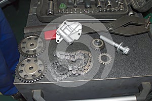 The elements of the new timing chain replacement kit are on a gray tool cart