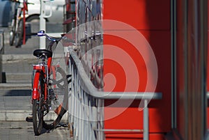 Elements of the urban environment with a bicycle, metal fences and part of the facade of the new building.