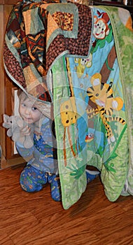 Elephant-loving toddler and his elephant peeking out of a blanket fort