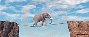 Elephant walks on slackline rope above a gap between two mountain peaks