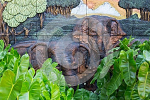 Elephants stone sculpture on the wall with jungle background in