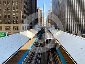 Elevated `el` train arriving at the Adams/Wabash station in Chicago south loop during spring morning