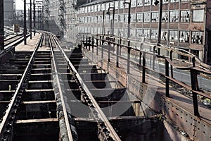 Elevated train tracks running alongside and abandoned industrial complex