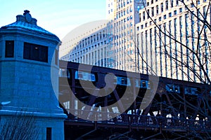 Elevated train travels over Chicago River and riverwalk on frigid January morning.