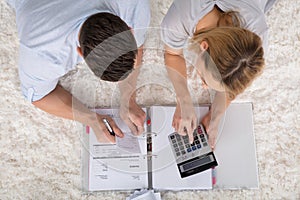Elevated View Of A Couple Calculating Invoice