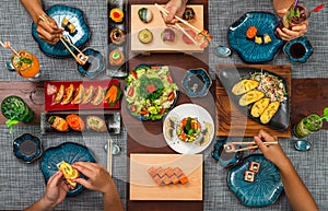 Elevated view of four person enjoying Japanese cuisine various side dishes and cocktails. Philadelphia, Tuna uramaki, Flower sush