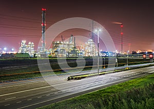 Elevated view on highway and illuminated petrochemical production plant at night