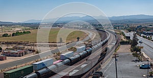 Elevated View of Long Freight Train on Tracks in Barstow, Route 66, with Scenic Mountain Backdrop