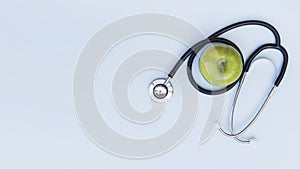 An elevated view of stethoscope around the green apple