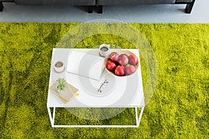 elevated view of table with laptop, coffee cups, apples in bowl, books, eyeglasses and plant
