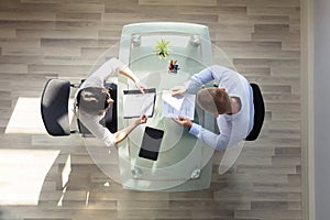 Elevated View Of Two Businesspeople Holding Resume