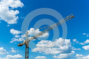 Elevating construction crane against the background of the cloudy sky.