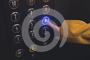 Elevator floor panel in building close-up. Woman hand touch and press the button on the panel with led lights