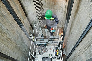 Lift machinist repairing elevator in lift shaft photo