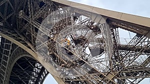 Elevator moving down with passengers on Tour Eiffel in Paris and people going down on stairs.
