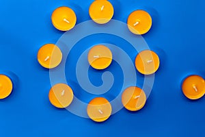 Eleven unlit mango scented candles in the shape of a circle lie on a blue background photo