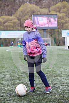 Eleven years old girl football player practicing with ball on artificial grass field