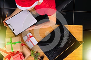 The elf receives an online e-mail by the kidney, and reads the list of gifts at the table with gift boxes. Christmas